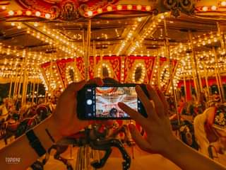 May be an image of one or more people, people riding a carousel and outdoors